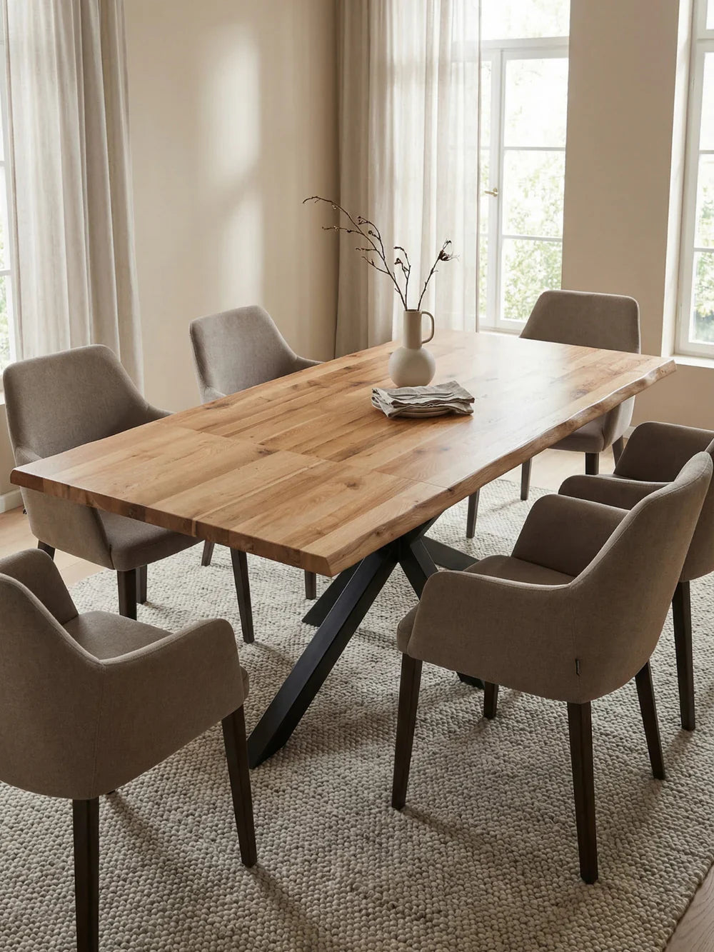 Uitschuifbare massief houten tafel van eiken met boomstamrand en grijze armleuningstoelen in een lichte eetkamer