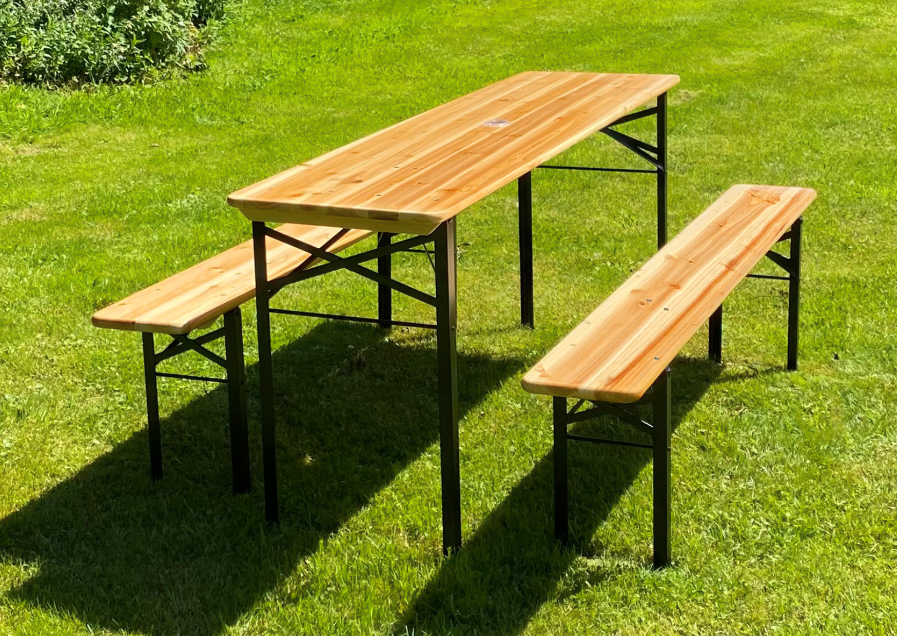 Inklapbare bierbankset van licht hout met tafel en twee banken op een groene weide