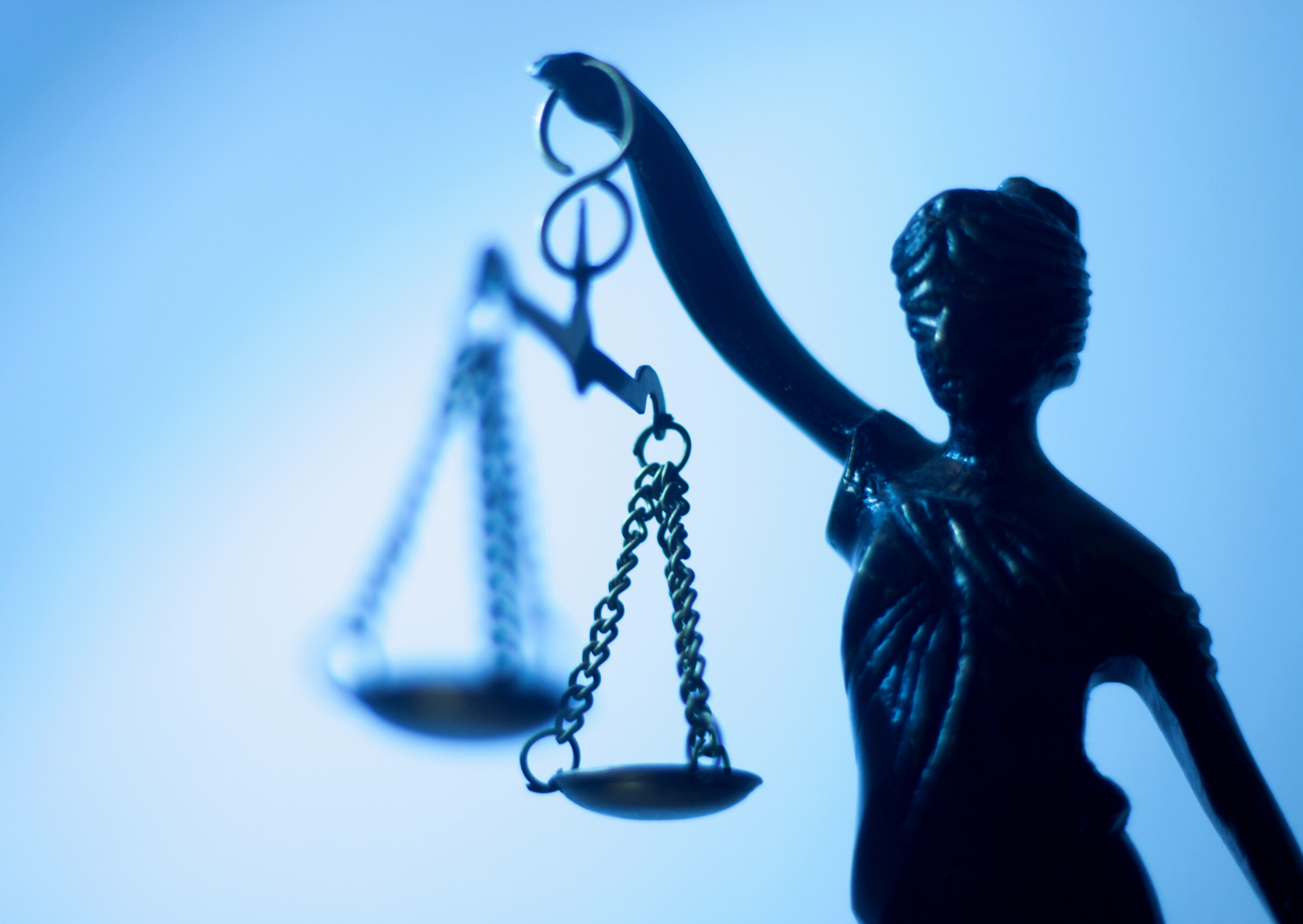 Bronzen beeld van Justitia met weegschaal voor een blauwe achtergrond als symbool voor deelnamevoorwaarden