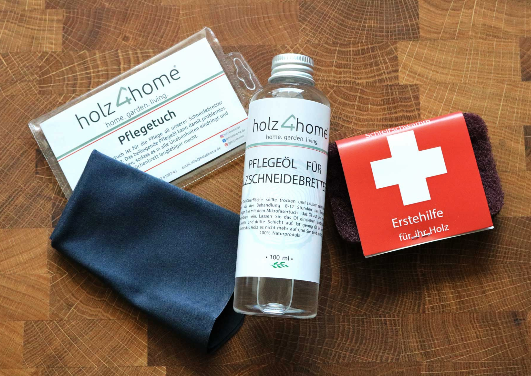 Onderhoudsset van holz4home met onderhoudsdoek, onderhoudsolie en schuurspons op een eikenhouten oppervlak