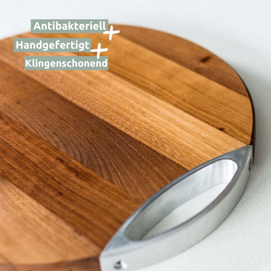 Detailopname van de ronde snijplank van berkenhout met gepolijste metalen greep, close-up