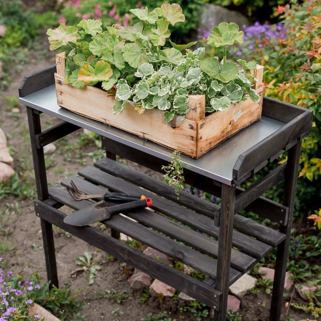 Houten plantentafel zwart met plantenbak, blik van bovenaf op zinken plaat en tuinschepjes op het werkblad