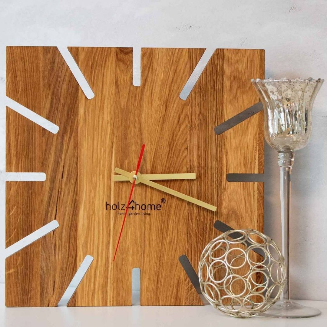 Wandklok Sunshine van eikenhout met stralendesign naast een kaarsenhouder en een zilveren bol als decoratie