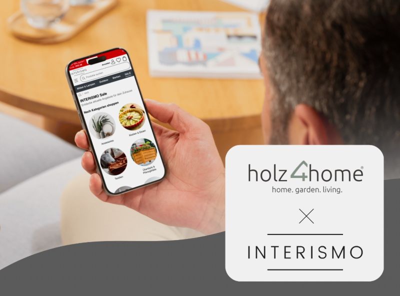 Man houdt een smartphone met de INTERISMO-webshop naast het holz4home-logo vast