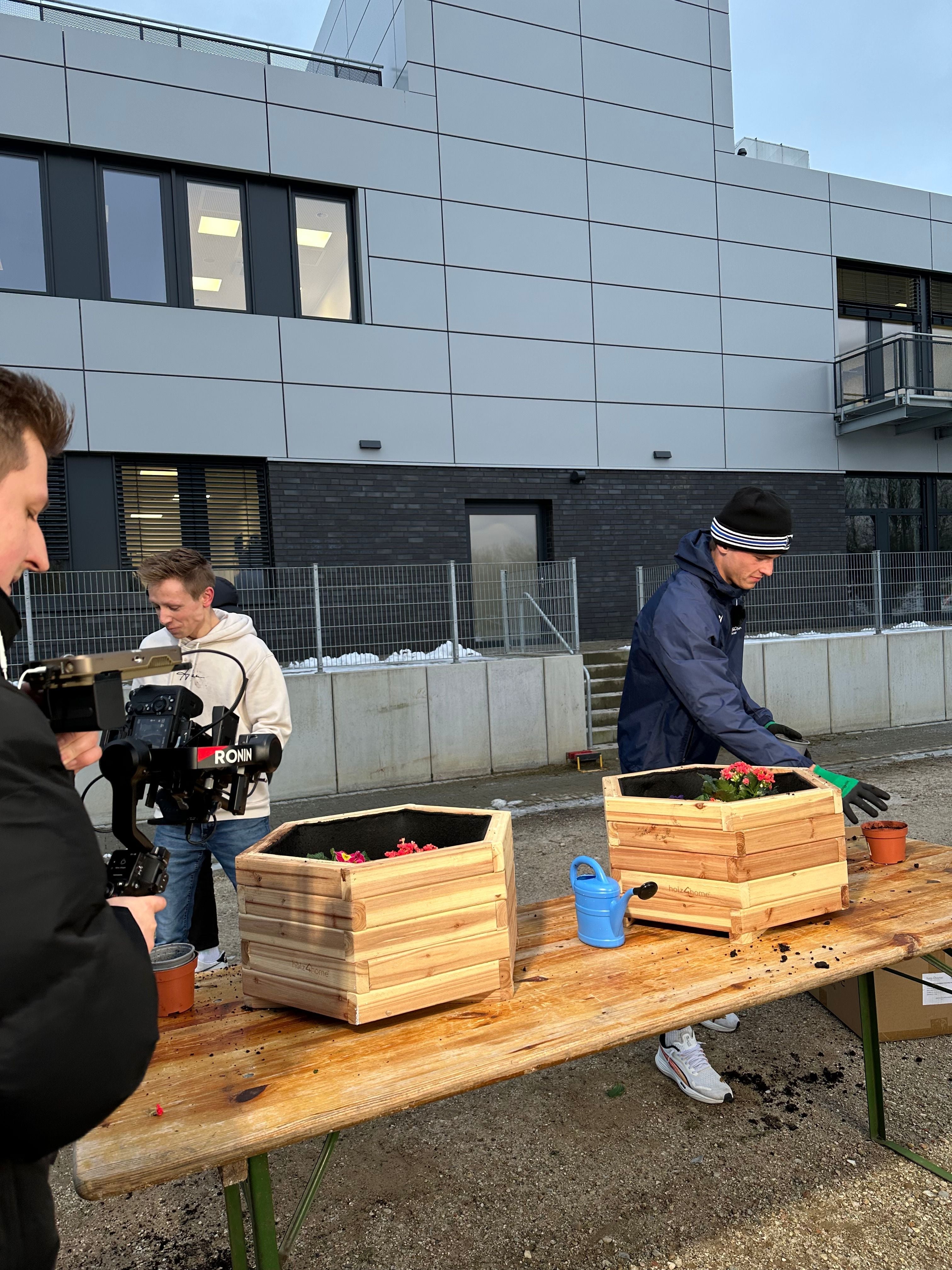 Team filmt het beplanten van houten plantenbakken op een bierbankset voor het bedrijfspand