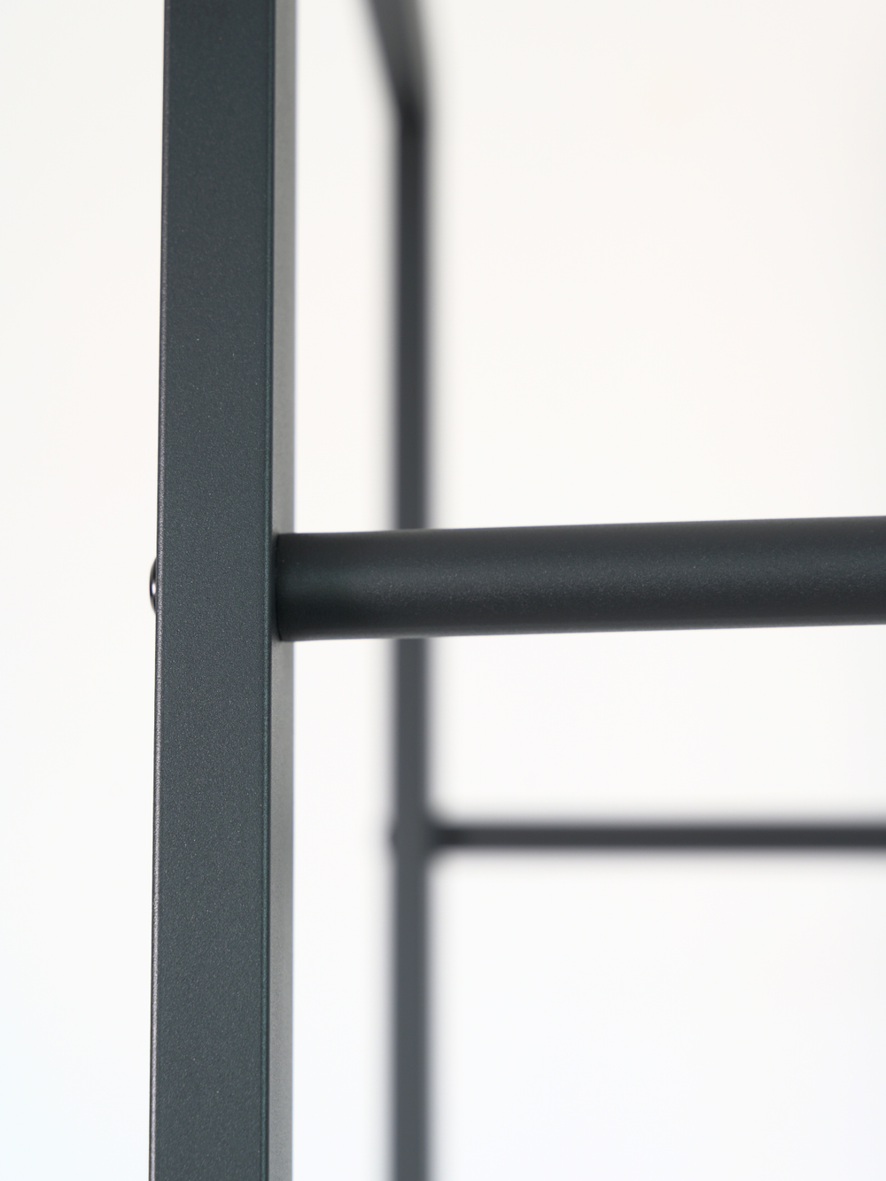 Detailopname van het antracietkleurige metalen frame van een haardhoutrek met poedergecoate dwarsverbinding