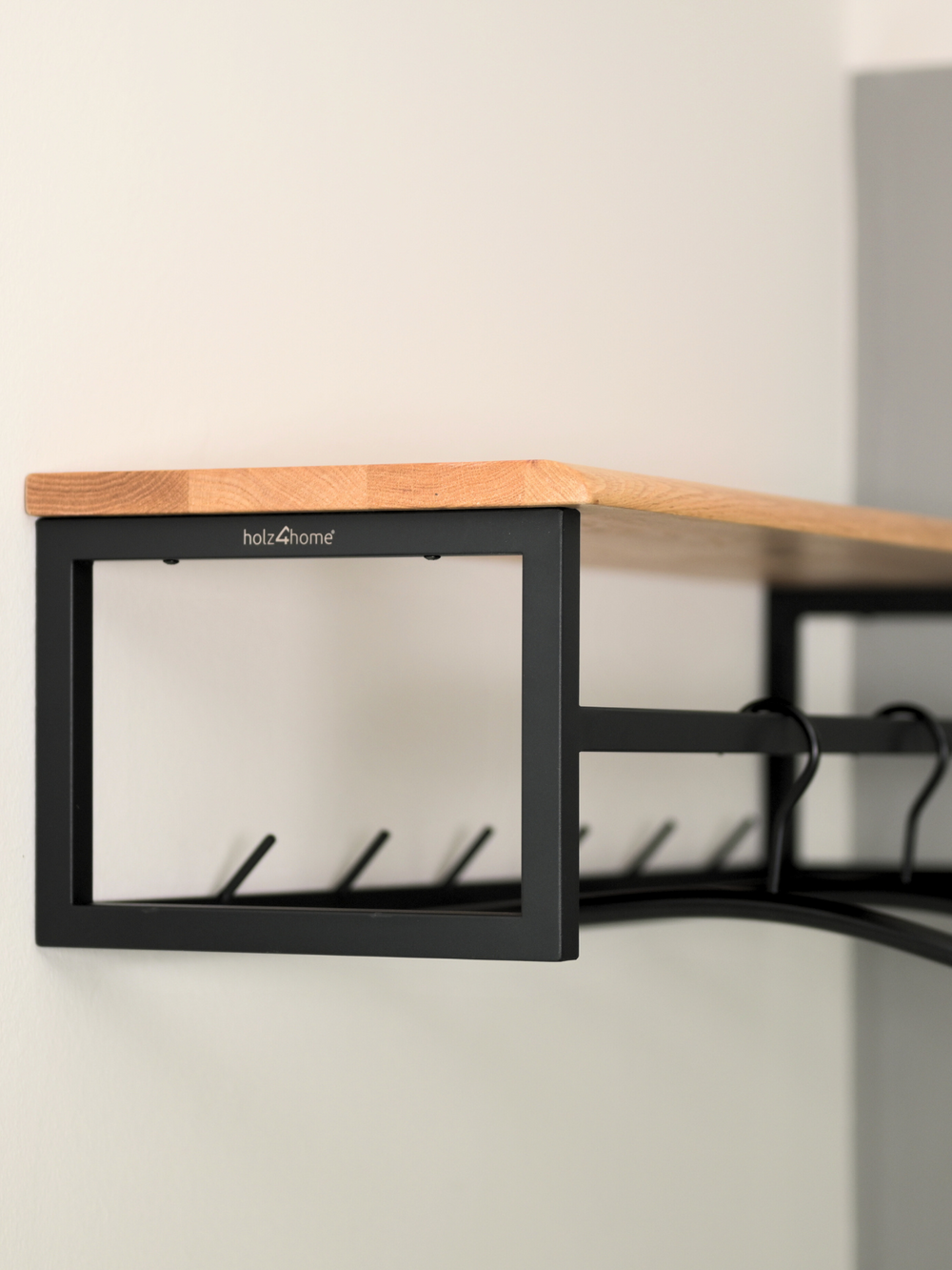 Zijaanzicht van de wandkapstok van eiken met zwart frame, holz4home-logo en daaronder gelegen haakstrip