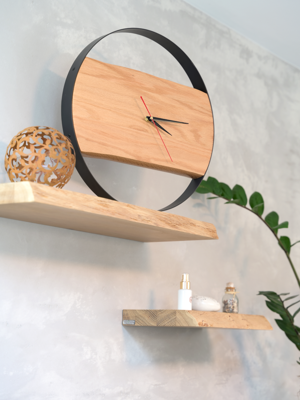 Ronde wandklok met stalen frame en eikenplank aan een betonnen muur boven twee zwevende houten rekken