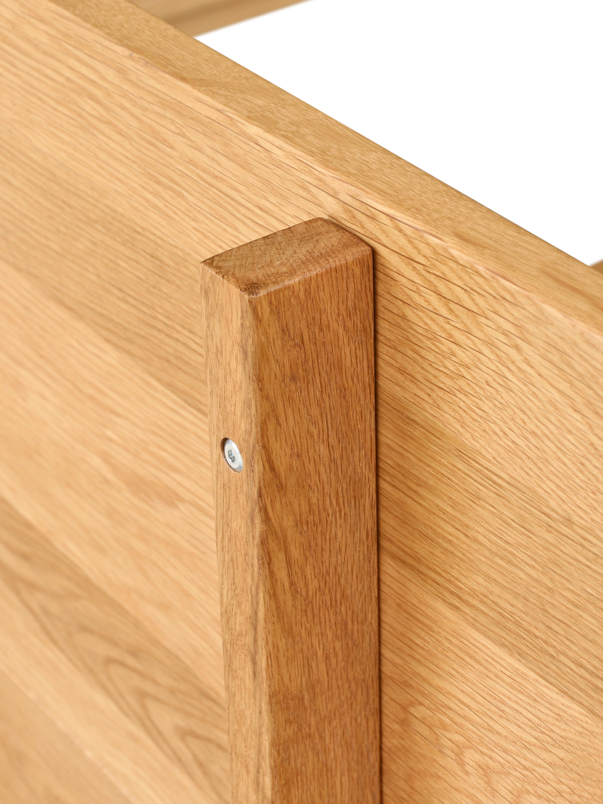 Detailopname van de verschroefde hoekverbinding tussen hoofdbord en frame van het eiken bed
