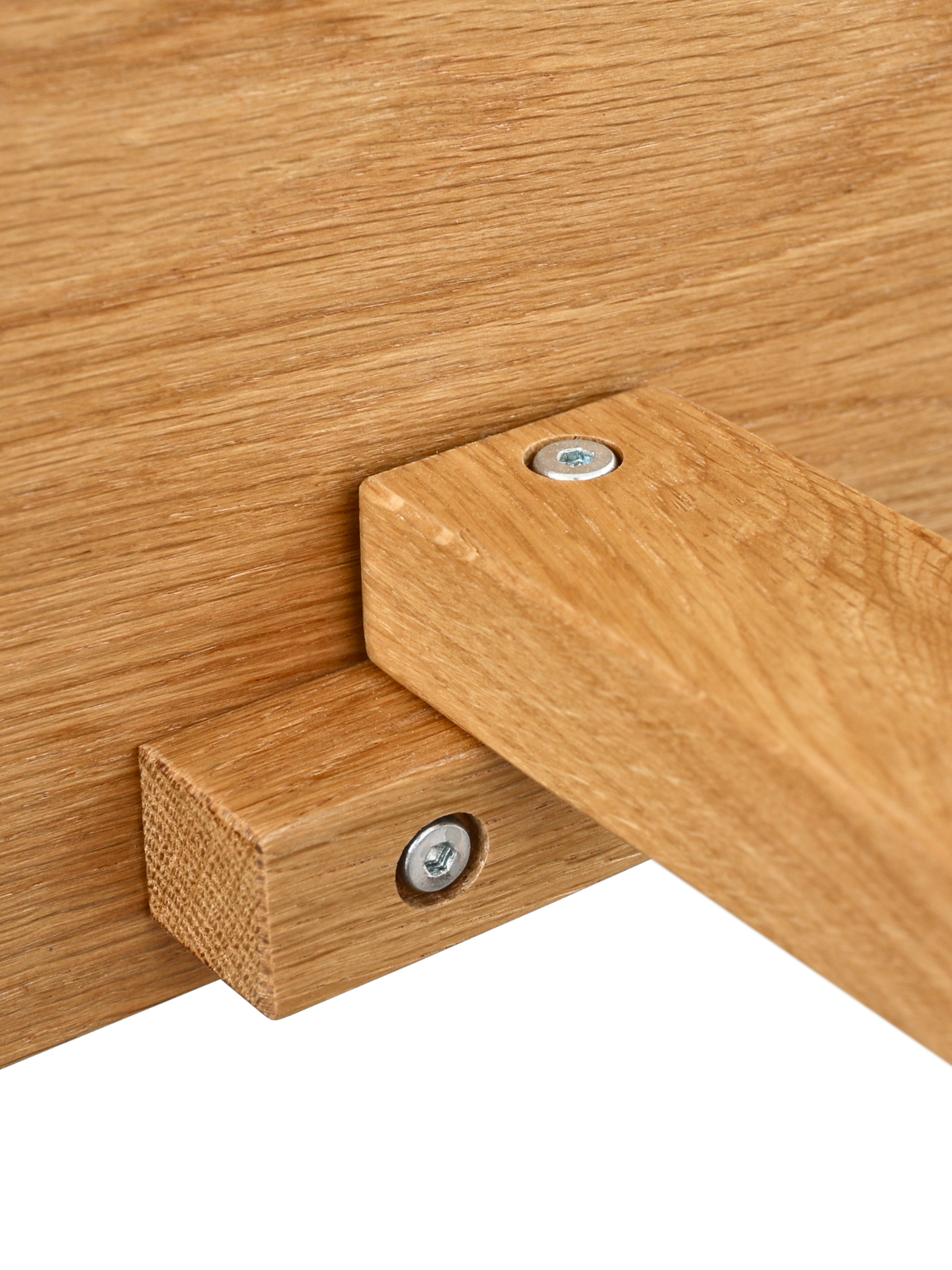 Detailopname van de vastgeschroefde verbinding tussen eikenhouten frame en gebogen houten poot van het bed