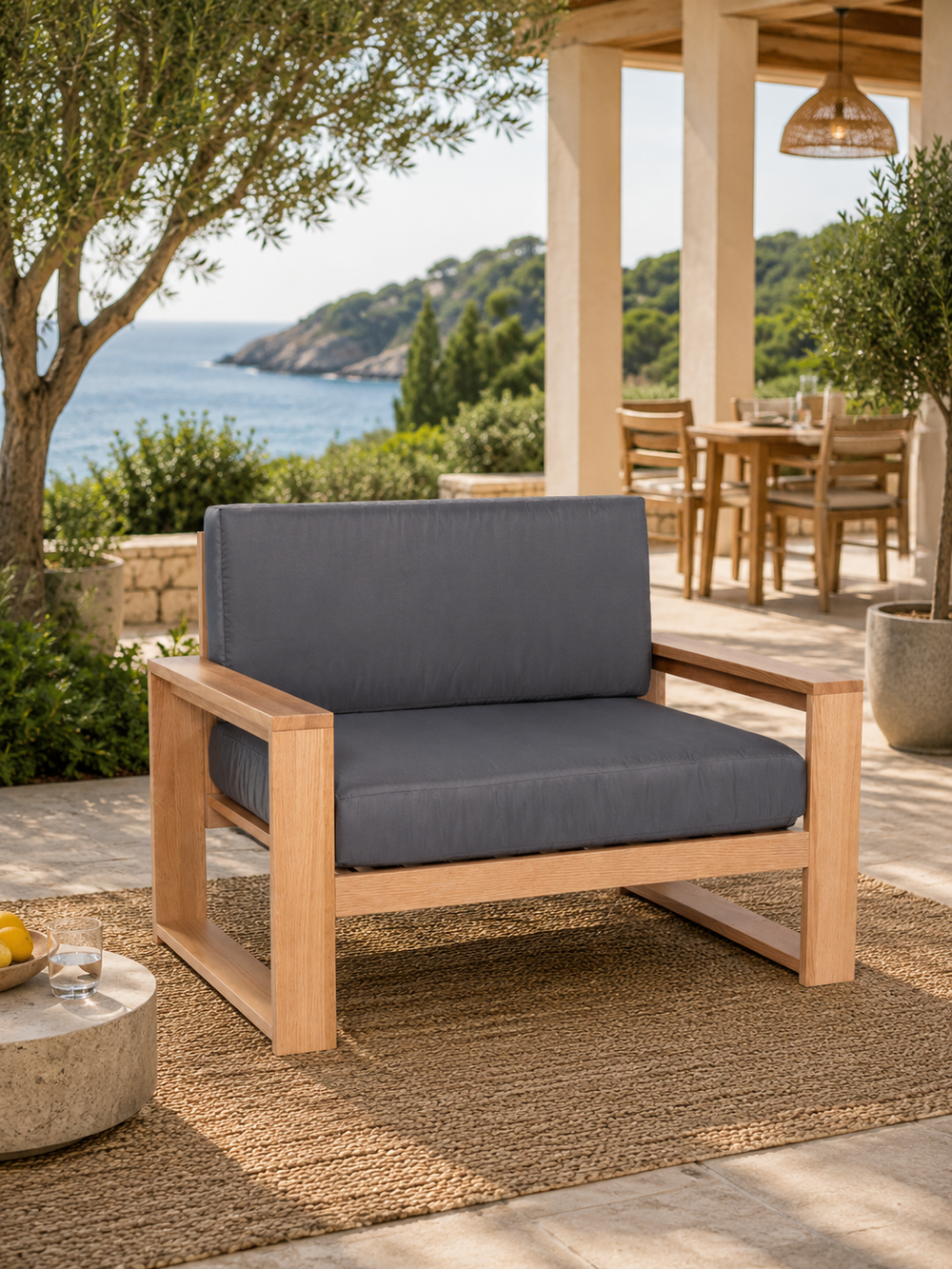 Tuinlounge-fauteuil van eiken met antraciet kussens op een mediterraan terras met zeezicht