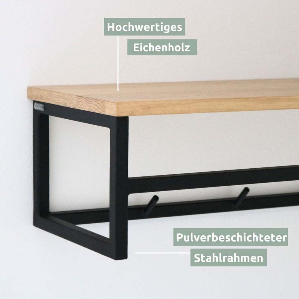 Detailopname van de eikenhouten plank en het poedergecoate zwarte stalen frame van de wandkapstok