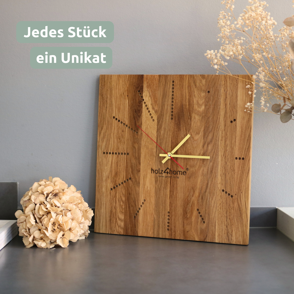 Wandklok Dots van eiken met gouden wijzers naast een gedroogde hortensia op een plank