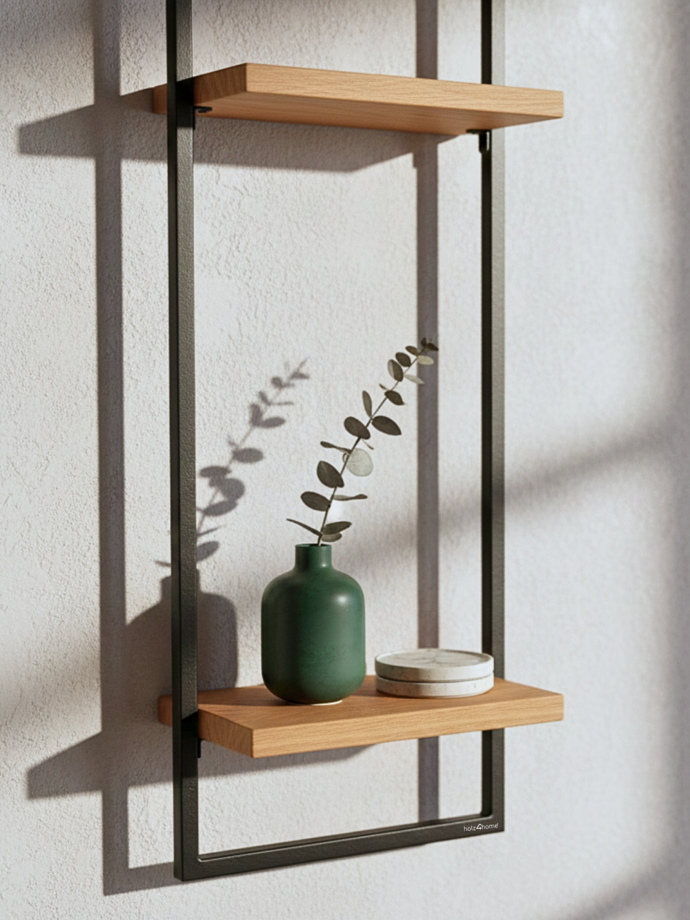 Detailopname van de onderste eikenhouten plank in het zwart omlijste wandrek High met groene vaas en eucalyptus