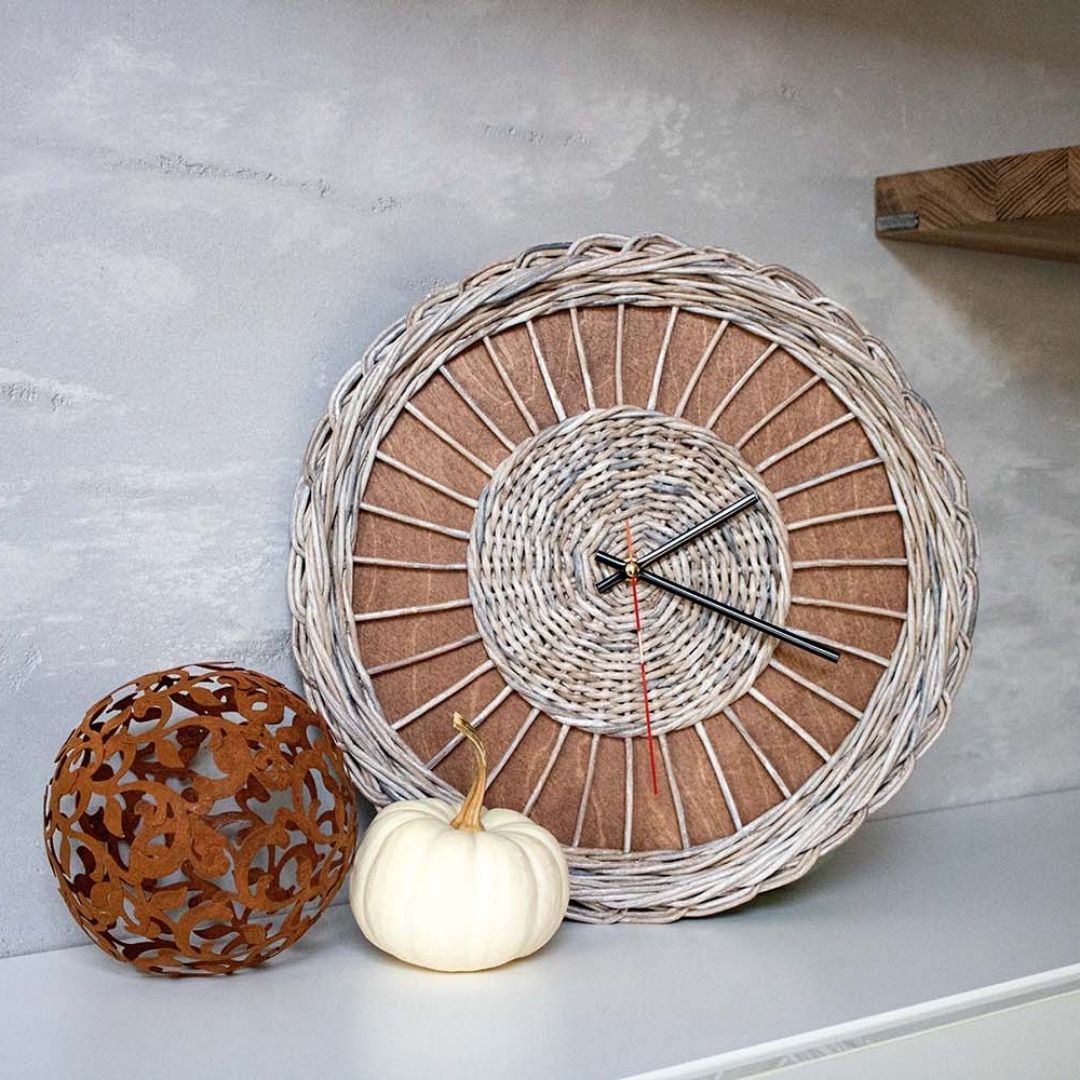 Rattan wandklok Weave getoond op een plank naast een witte pompoen en een versierde decoratieve bol