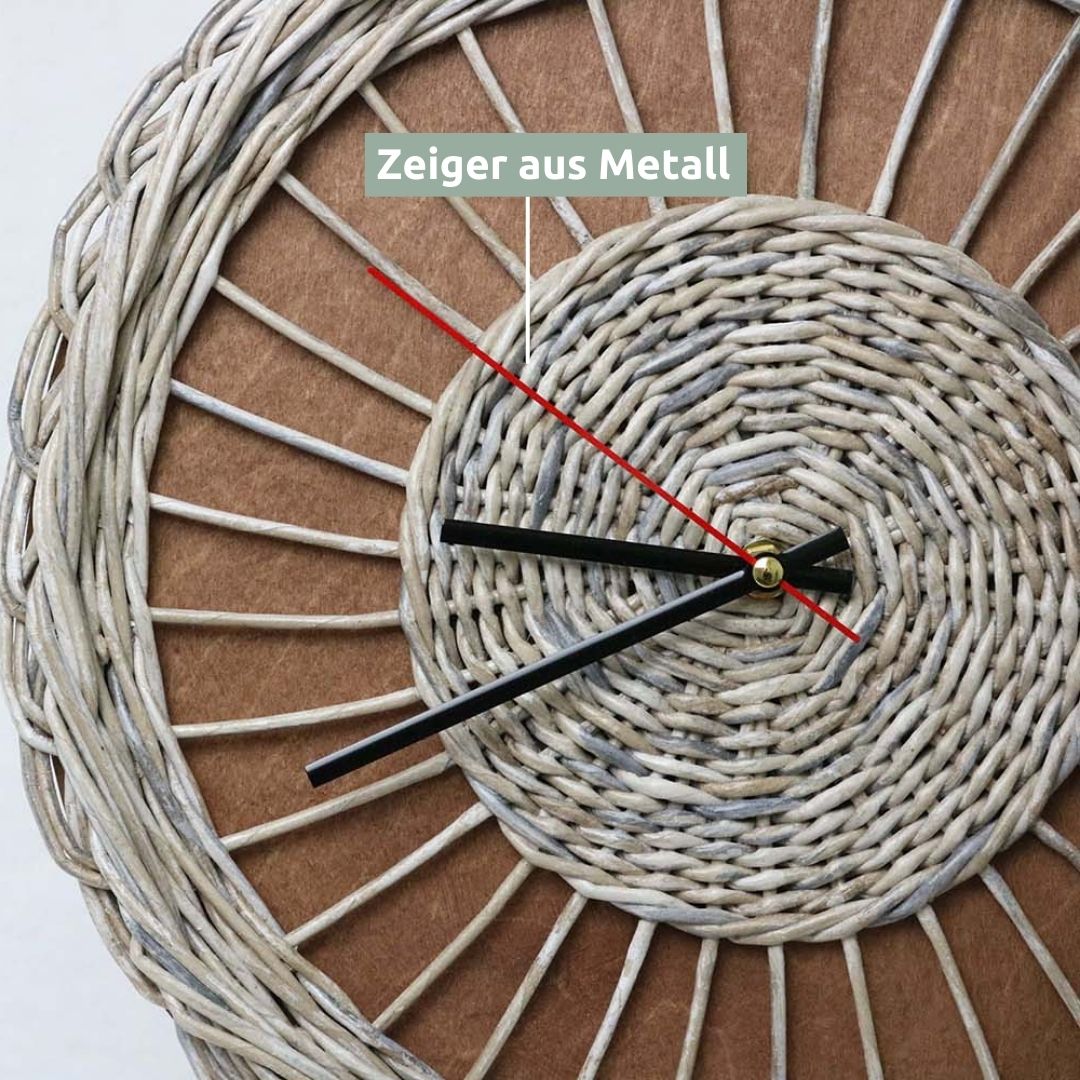 Close-up van de zwarte metalen wijzers en de rode secondewijzer op de rattan wandklok Weave