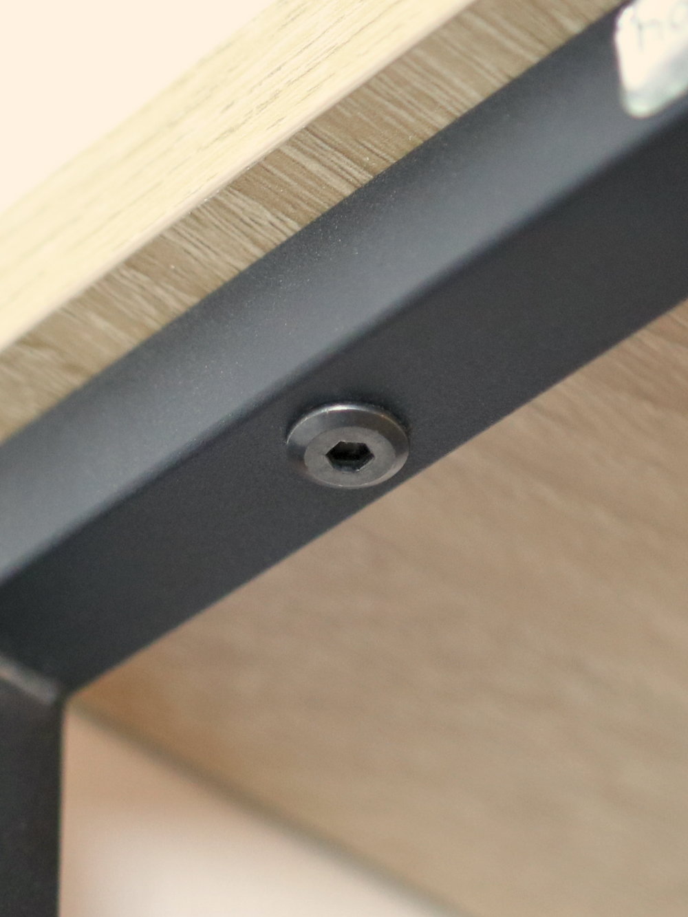 Close-up van de inbusschroef aan het zwarte metalen frame onder de eiken legplank