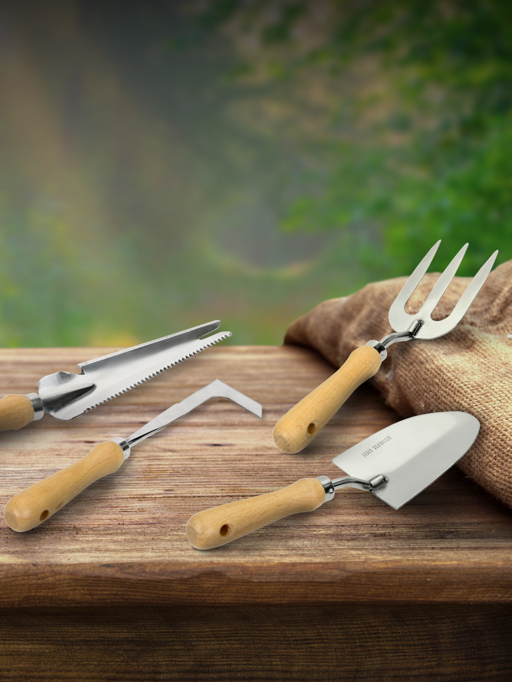 Vierdelige tuingereedschapsset van rvs met houten handvatten op een houten tafel met jutezak