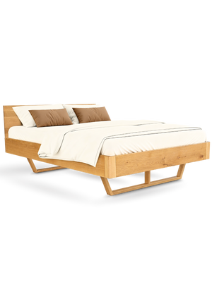 Massief houten bed van eiken met gebogen hoofdbord en afgeronde sledepoten, opgemaakt met beddengoed