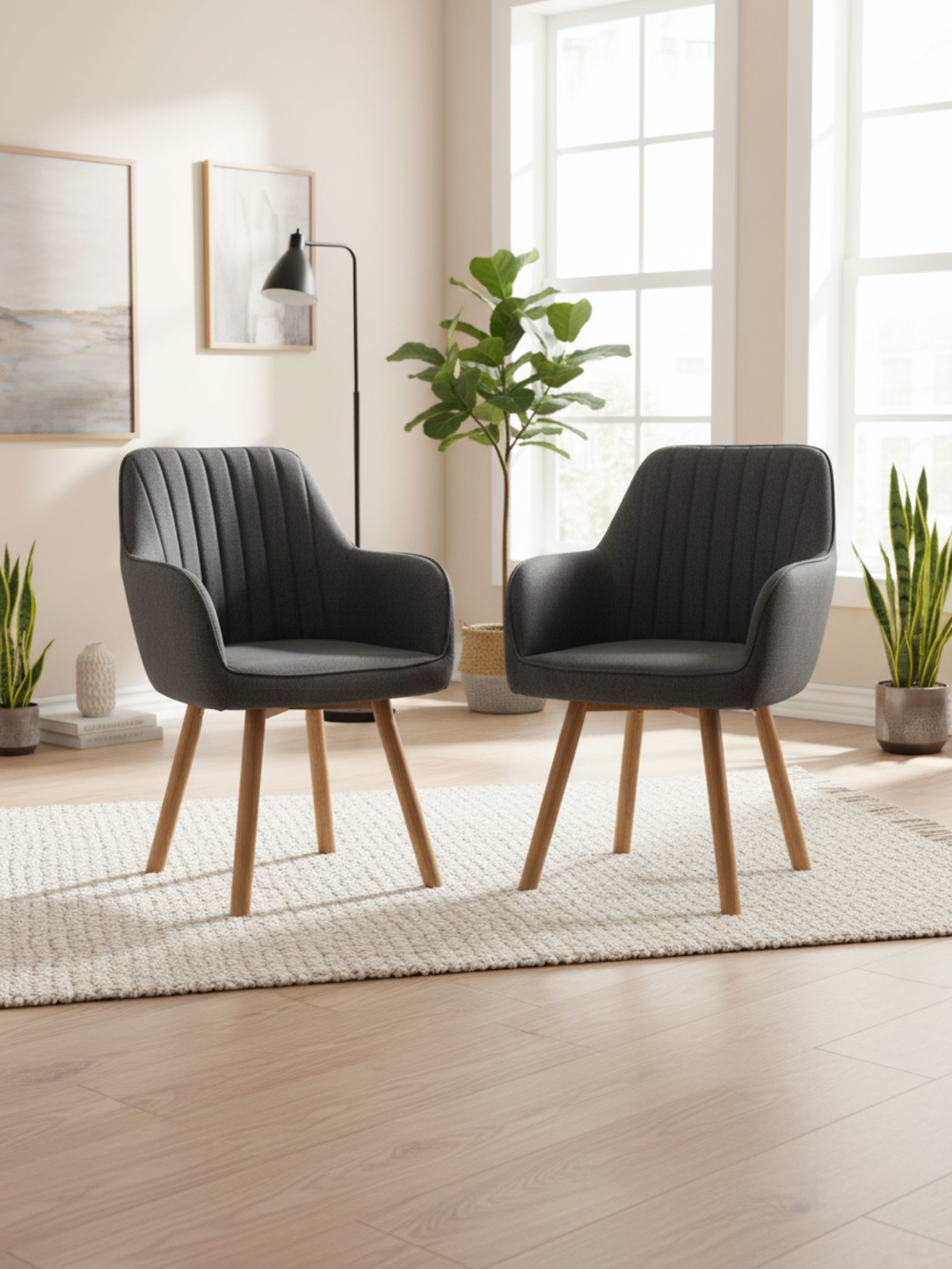 Twee antracietkleurige eetkamerstoelen met eikenpoten in de lichte woonkamer met kamerplant en vloerlamp