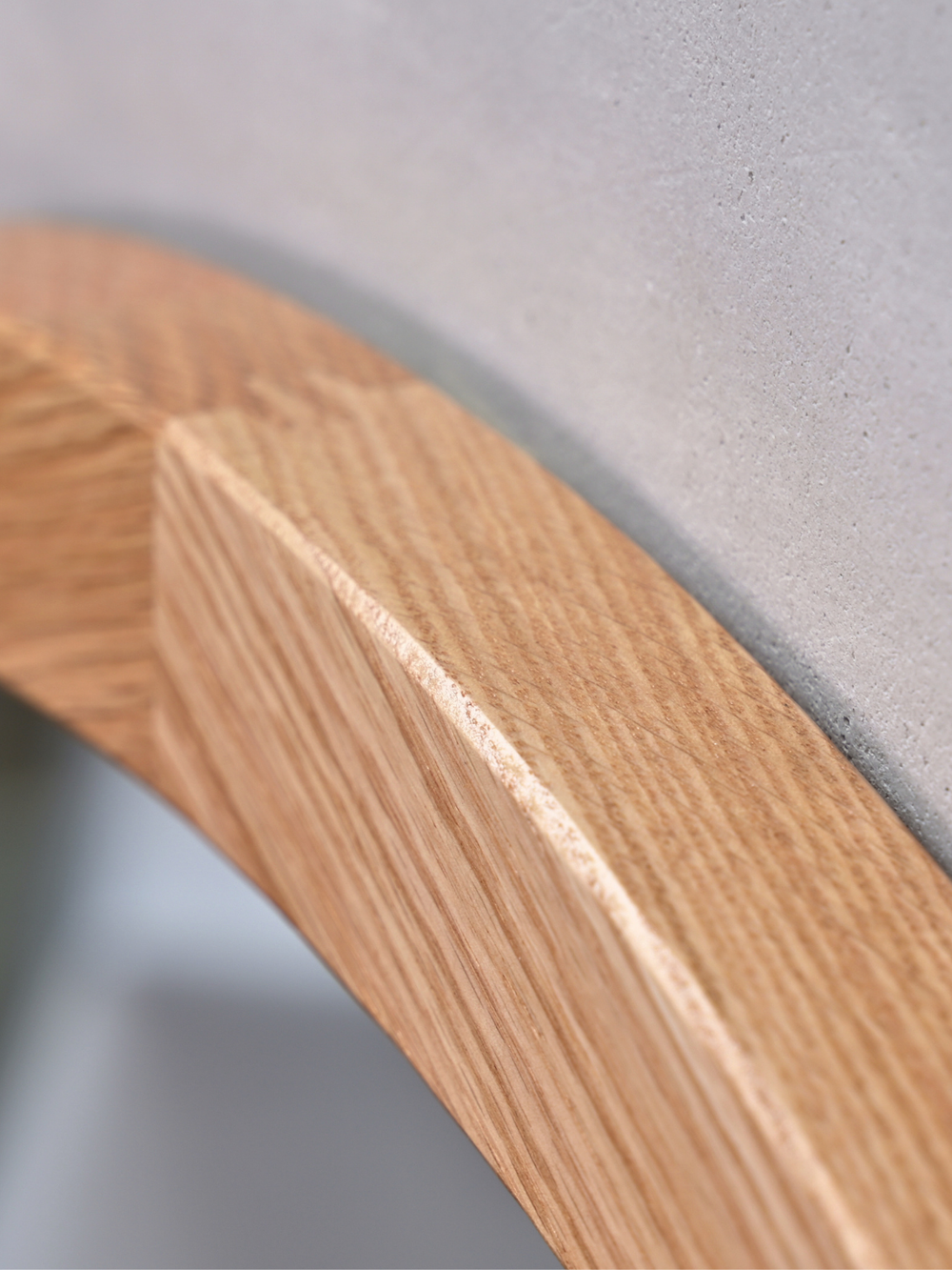 Detailopname van de verstekverbinding van de ronde eikenhouten lijst bij de wandspiegel voor grijze muur