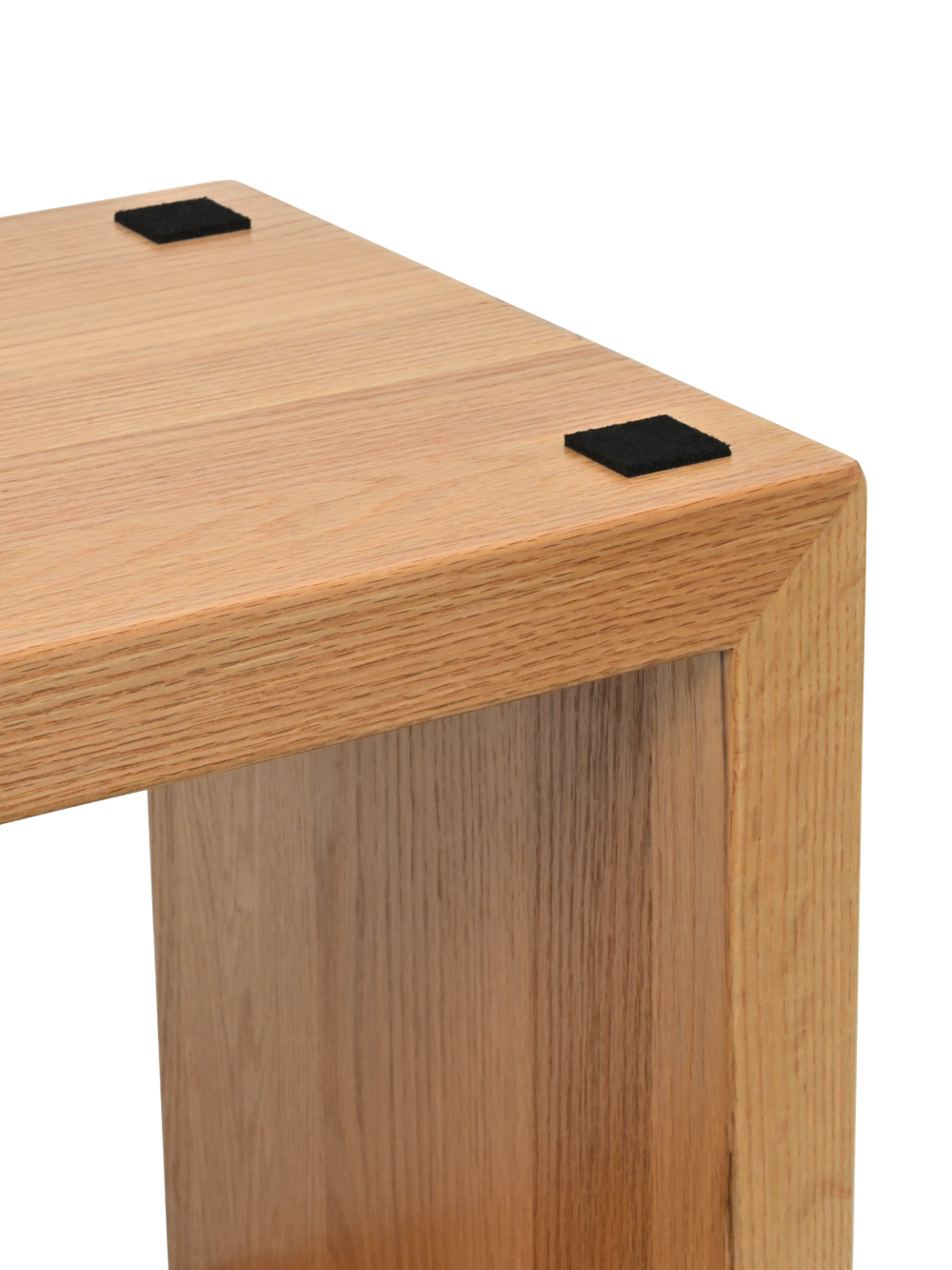 Close-up van de bovenhoeken van nachtkastje Cube van eiken met zwarte viltglijders