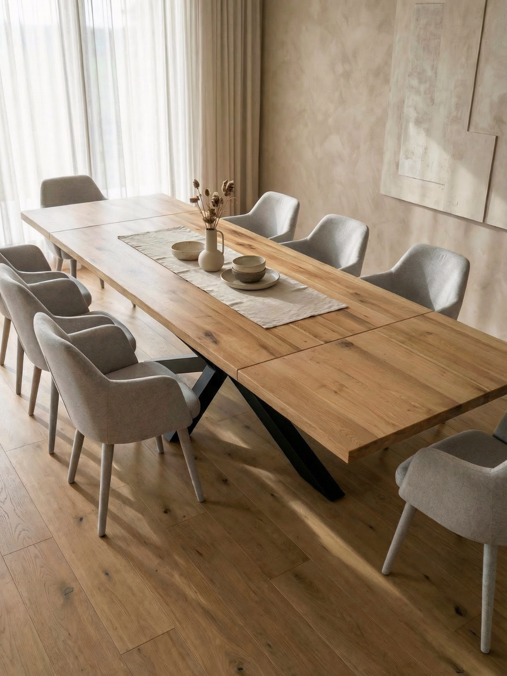 Uittrekbare eikenhouten tafel met Spider-onderstel in lichte eetkamer met grijze gestoffeerde stoelen en houten vloer