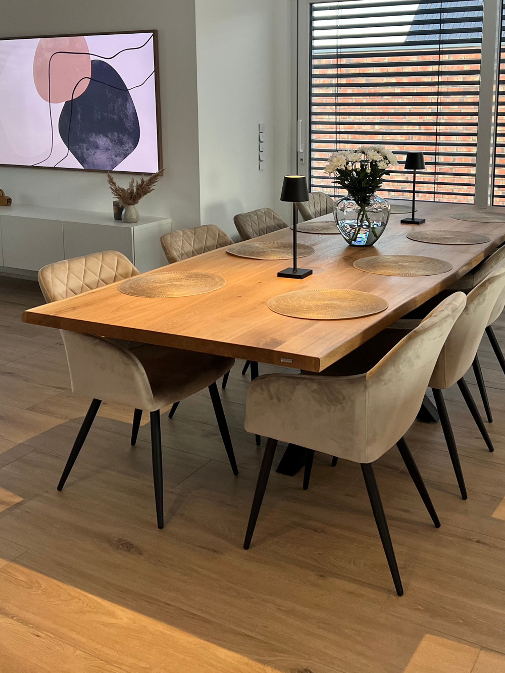 Sfeervolle eetkamer met eettafel van massief eiken met boomstamrand, gedekt met stoelen en decoratie bij het raam