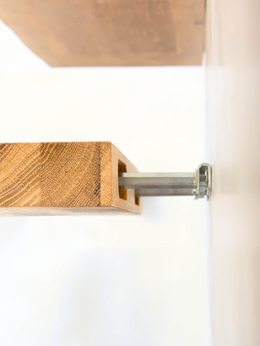 Zwevend wandrek van eiken, detail van de onzichtbare wandbevestiging met metalen staaf in de boring
