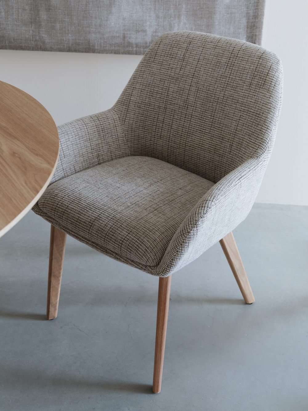 Armleuningstoel Loua in bruin aan een ronde eettafel van eiken in een lichte, moderne eetkamer