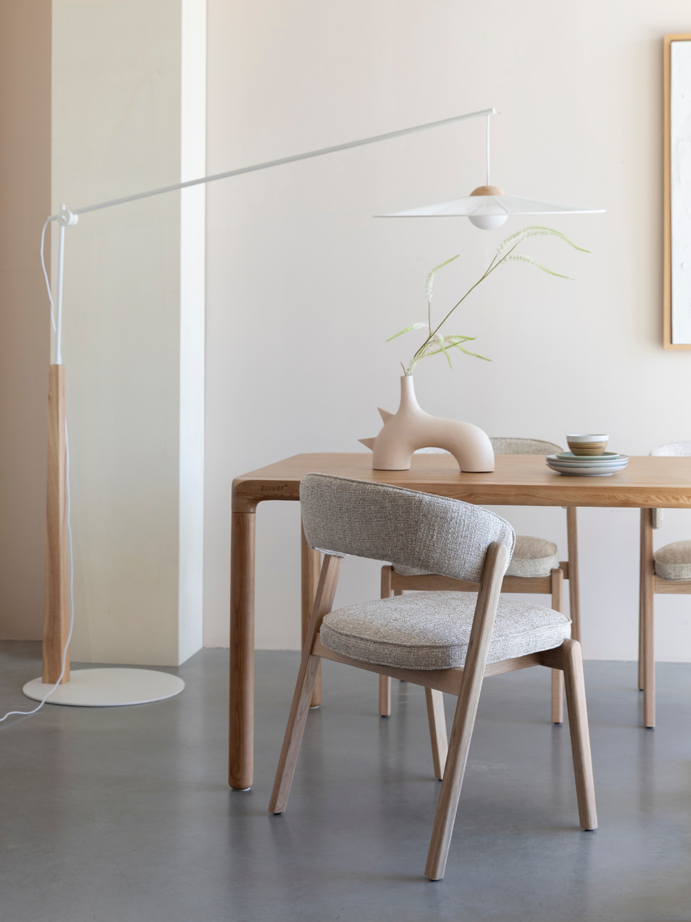 Eetkamerstoel Bright in beige aan een eettafel van eiken in een lichte, minimalistische eetkamer