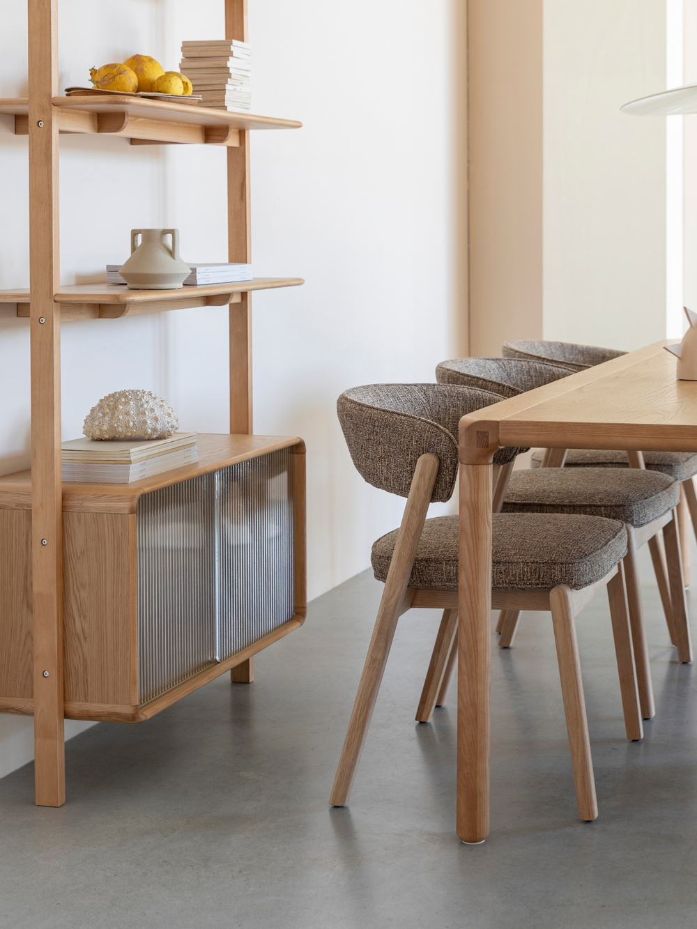 Eetkamerstoelen Bright in bruin aan een eettafel van eiken naast een open houten rek in de eetkamer
