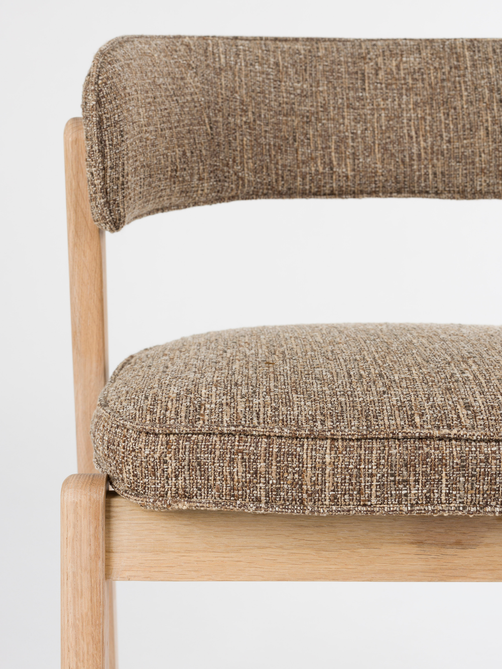 Close-up van het gestoffeerde zitvlak en de rugleuning van bouclé bij de eetkamerstoel Bright in bruin