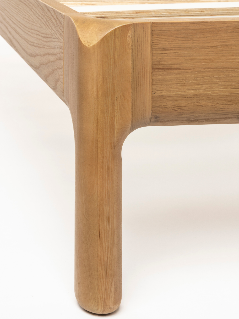 Detailopname van de gedraaide poot en de framehoek van essenhout bij het bed, close-up