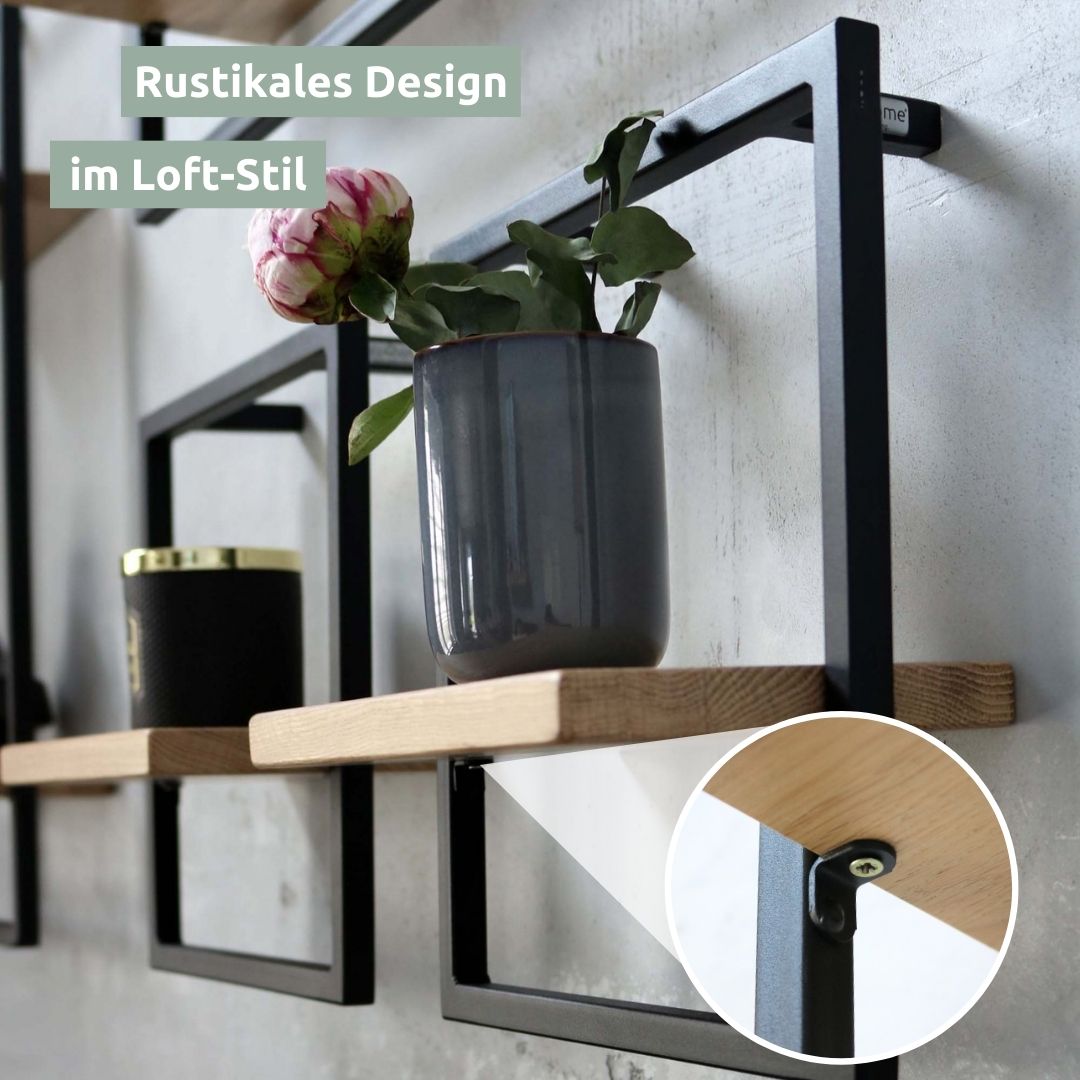 Meerdere zwart omlijste wandrekken aan betonnen muur met vaas en pioenroos, rustiek design in loft-stijl
