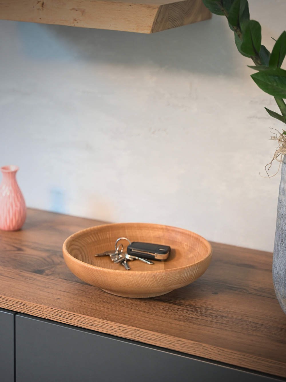 Houten schaal van essenhout als sleutelschaal met sleutelbos op een sideboard van donker hout