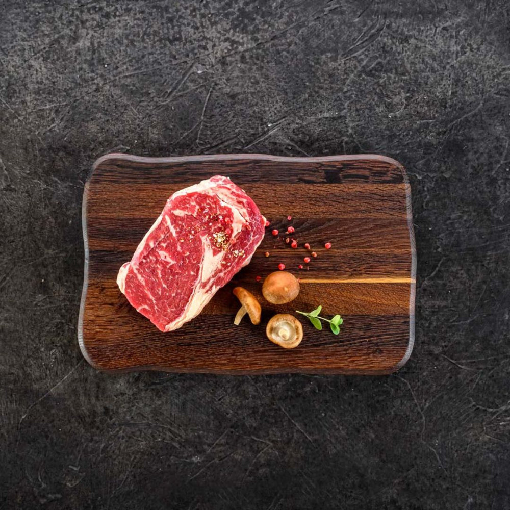 Snijplank Basic van donker eikenhout met rauw steak, peper en champignons aangericht