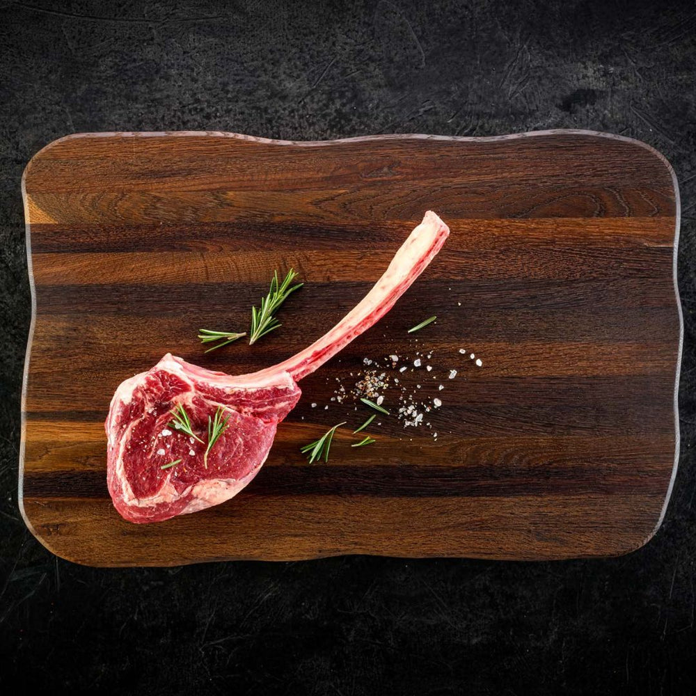 Rauwe tomahawksteak met rozemarijn en zout op donkere steakplank Master van eikenhout