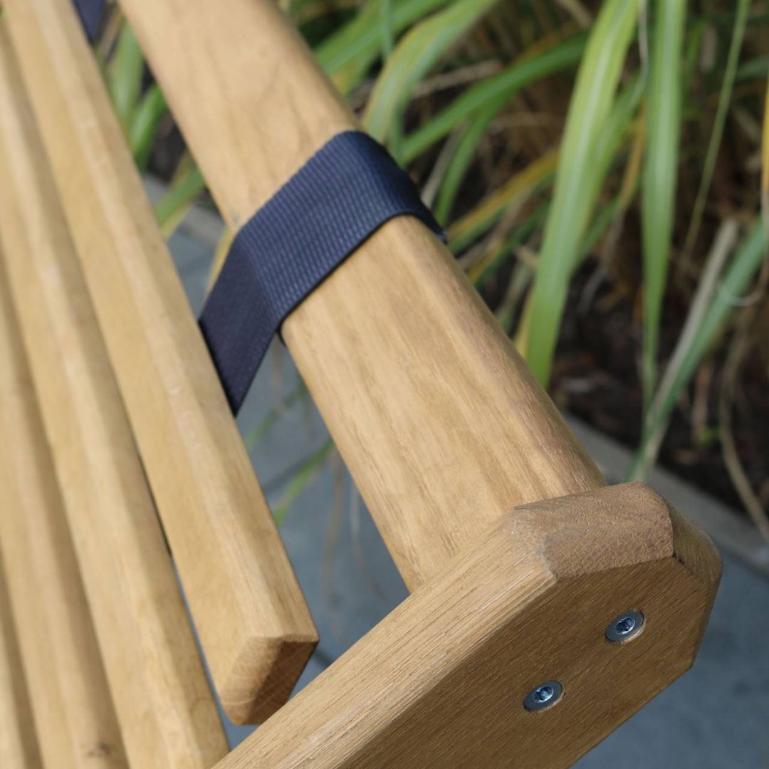 Close-up van de blauwe band en de vastgeschroefde armleuning van de eikenhouten ligstoel