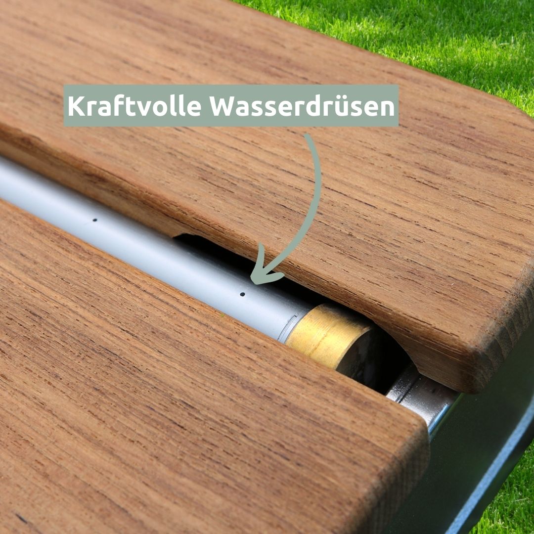 Close-up van de krachtige waterstralen aan de aluminium buis tussen de teakhouten lamellen van de vloerdouche