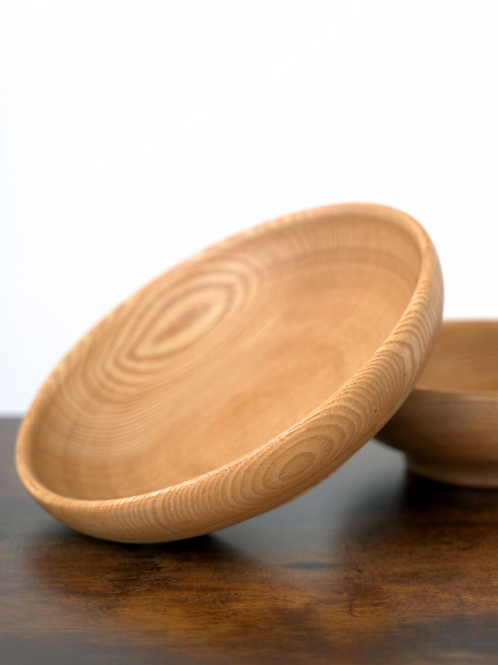 Close-up van twee houten schalen van essenhout met fijne jaarring-nerf op een houten tafel
