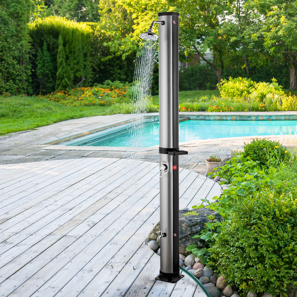 Zilveren outdoor zonnedouche bij het zwembad op houten terras in de tuin met stromend water